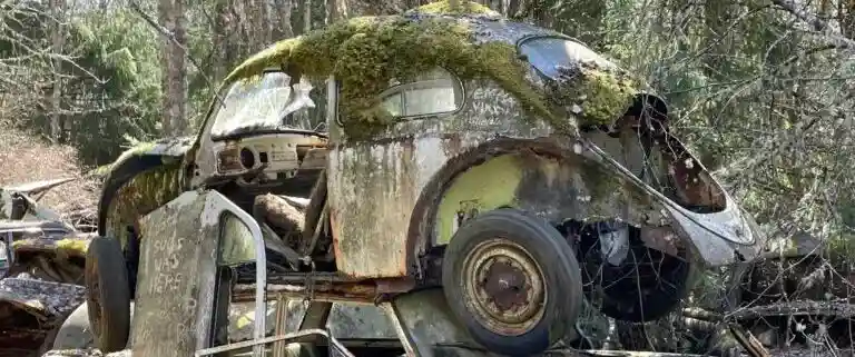 Skrotbil på återvinningsanläggning där metaller som stål och aluminium återvinns och påverkar värdet på bilen.